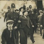 Sepia photograph of a person being arrested by police