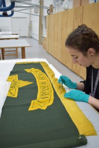 PHM Conservator Kloe Rumsey conserving a Wrexham Veteran Association Standard