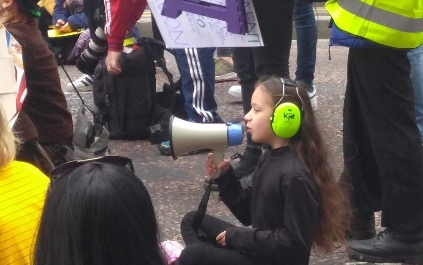 Image of A child sat down with a megaphone and ear defenders