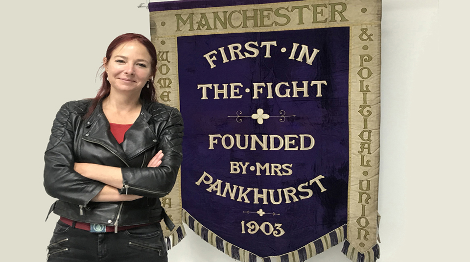 Image of Professor Alice Roberts with Manchester suffragette banner at People's History Museum