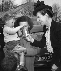 Photo of Dr Edith Summerskill presenting a bottle of Welfare Foods Service free orange juice, 1950