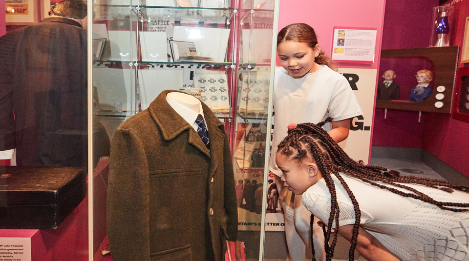 Image of Visitors viewing Michael Foot's Donkey Jacket from 1981, on display in Main Gallery Two at People's History Museum