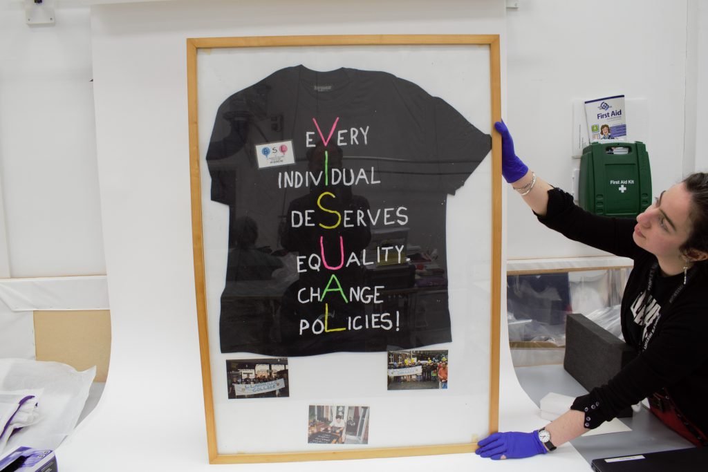 VISUAL t-shirt, 2002 with PHM Senior Conservator Kloe Rumsey. On loan from British Deaf History Society Deaf Museum. Image courtesy of People’s History Museum
