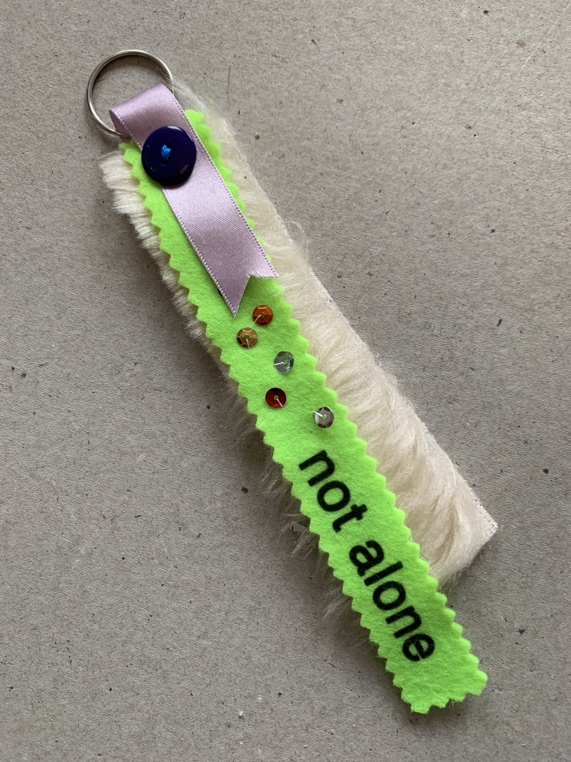 Keyring made from fabric with the words 'not alone' at The Fabric of Protest workshop at People's History Museum.