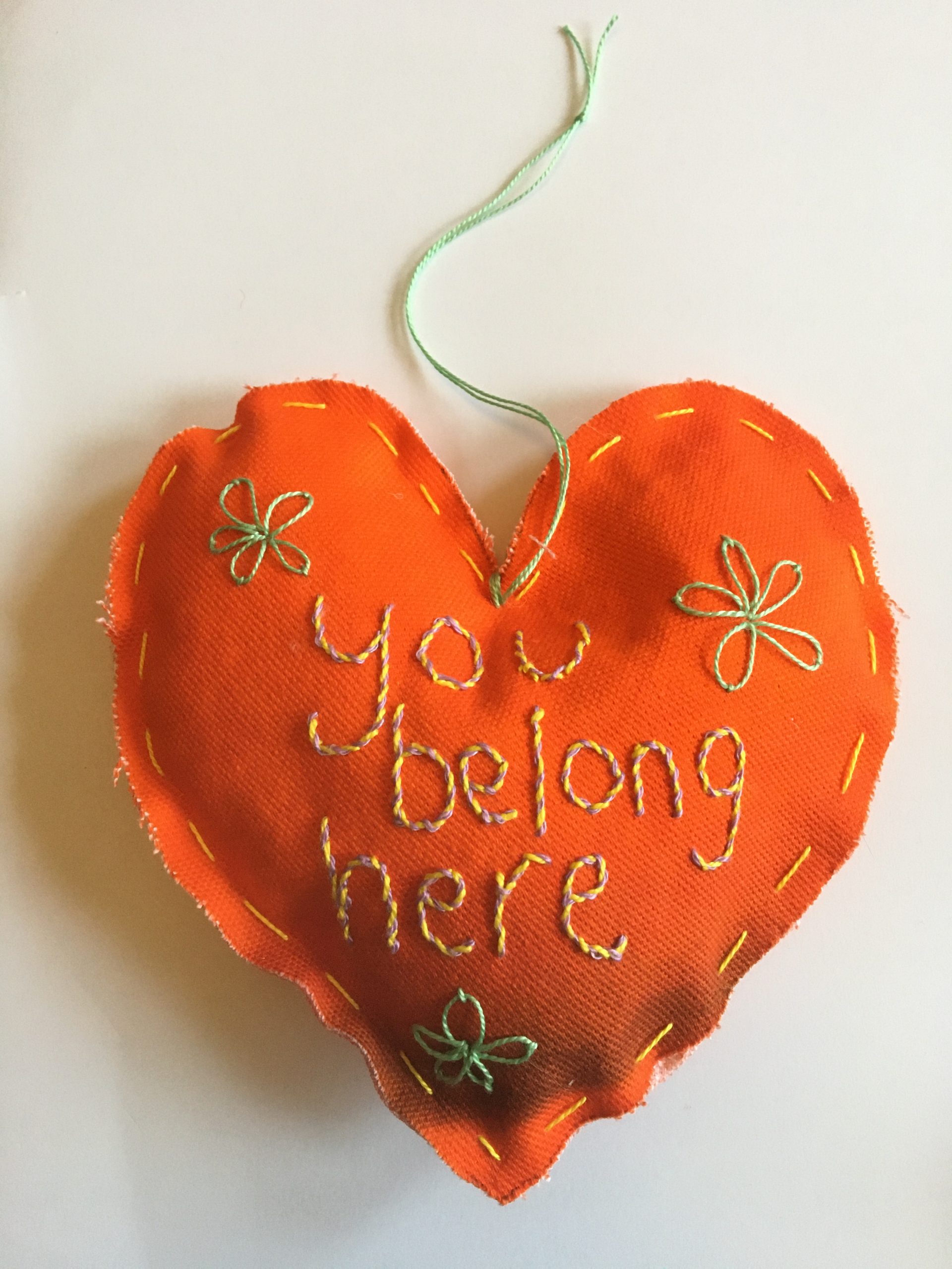 Heart shaped textile creation stitched with the words 'you belong here', made at The Fabric of Protest workshop at People's History Museum.