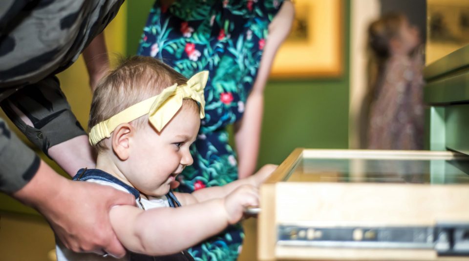 Image of toddler opening display drawer in the main galleries at People's History Museum.
