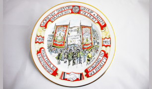 Image of a plate with an illustration of people marching with placards below three large traditional banners. The text reads: Womens’ Support Group & NUM Manvers Colliery.