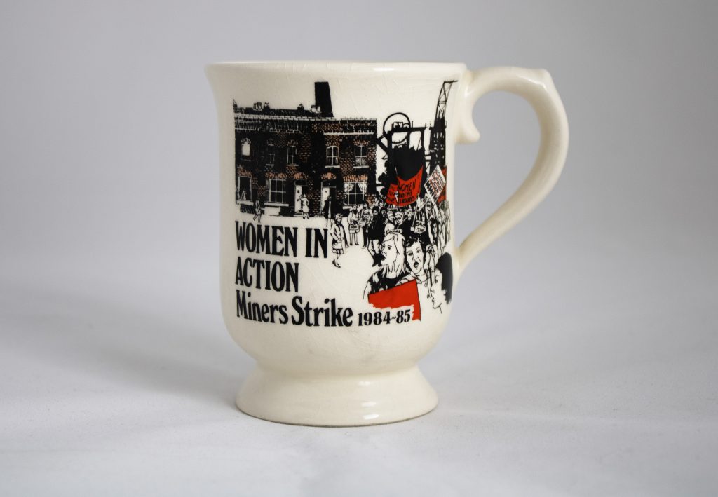 A mug with an illustration of a march and a colliery. Text reads: Women in Action Miners Strike 1984-85.