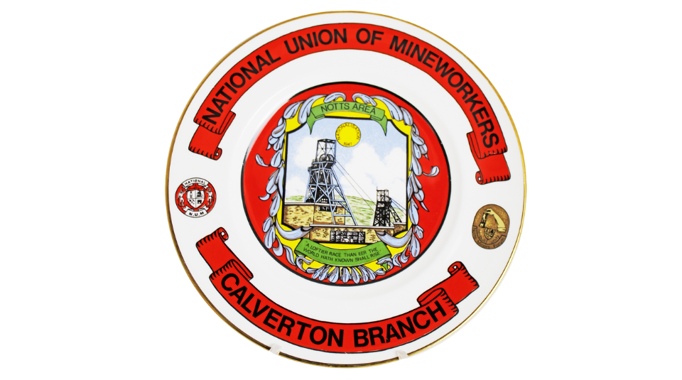 A white and red plate with an illustration of a pit head. The text reads ‘National Union of Mineworkers Calverton Branch’.