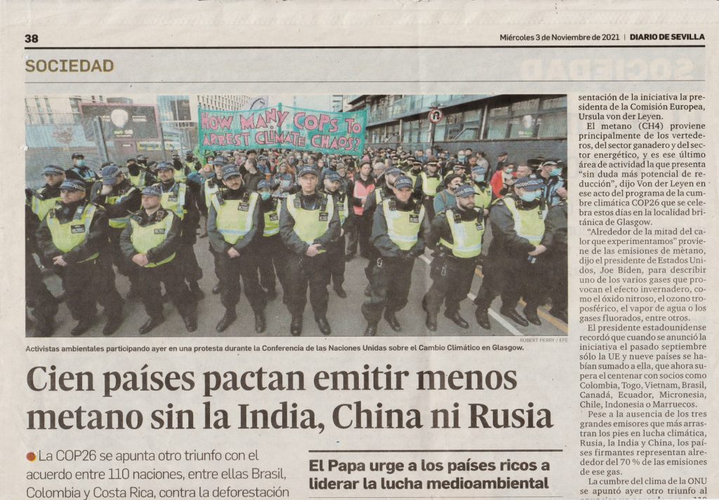 Spanish newspaper article featuring a photo of the How Many Cops To Arrest Climate Chaos? banner, 2021.