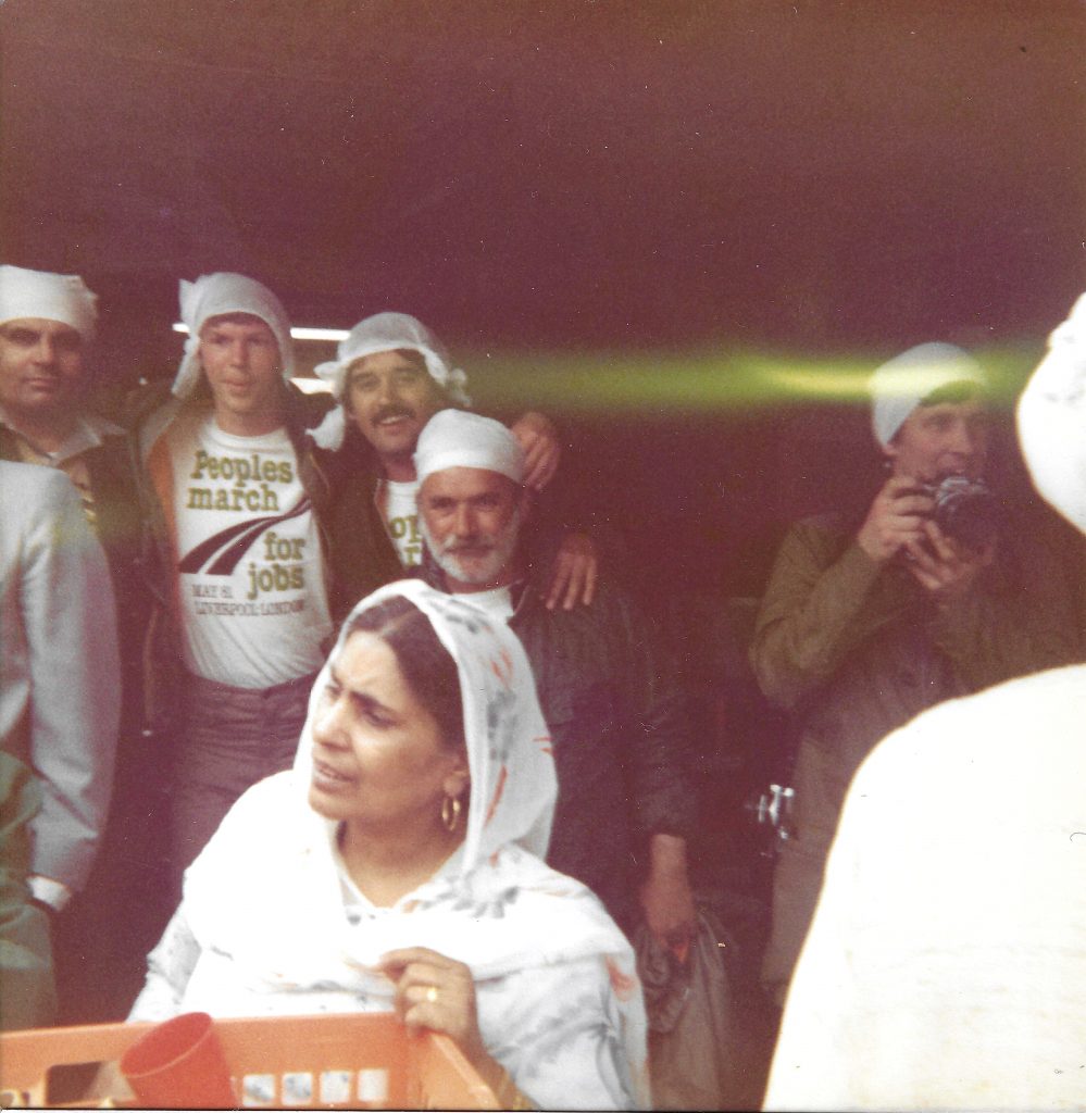 Colour photograph of a group of people wearing white headscarves and People’s march for jobs t-shirts.