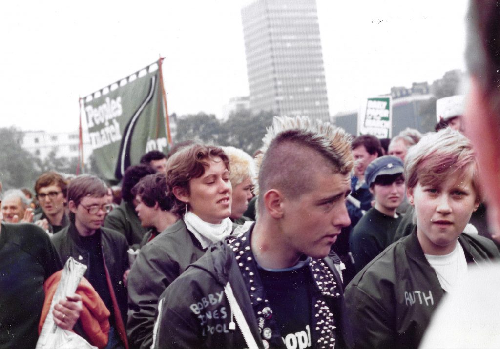 Colour photograph of a group of people marching in a protest. There is a banner with the text: 'People’s march for jobs'.