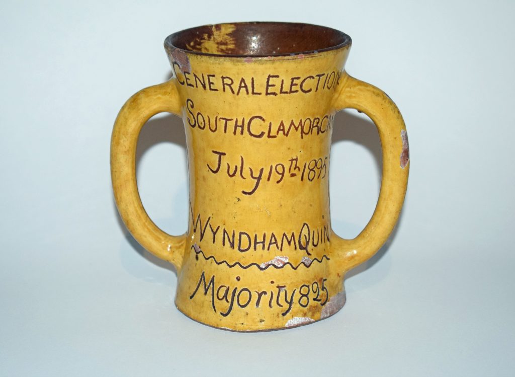 Mustard ceramic mug with engraved brown text reading: 'General Election, South Glamorgan, July 19th 1895, Wyndham Quin, Majority 825'.