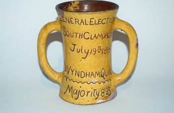 Image of Mustard ceramic mug with engraved brown text reading: 'General Election, South Glamorgan, July 19th 1895, Wyndham Quin, Majority 825'.