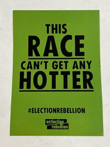 A green portrait poster with black text: This Race Can’t Get Any Hotter #ElectionRebellion Extinction Rebellion.