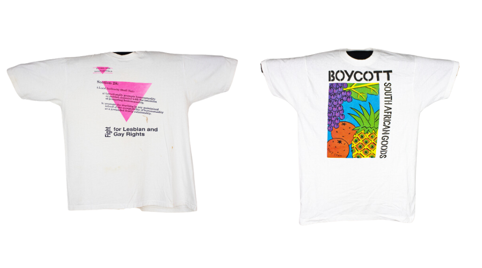 Left to right A white t-shirt with a pink triangle. Including black text: Fight for Lesbian and Gay Rights and a white t-shirt with a colourful illustration of fruit with black text: Boycott South African Goods