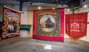 Image of Three big colourful textile banners hanging in a large gallery space.