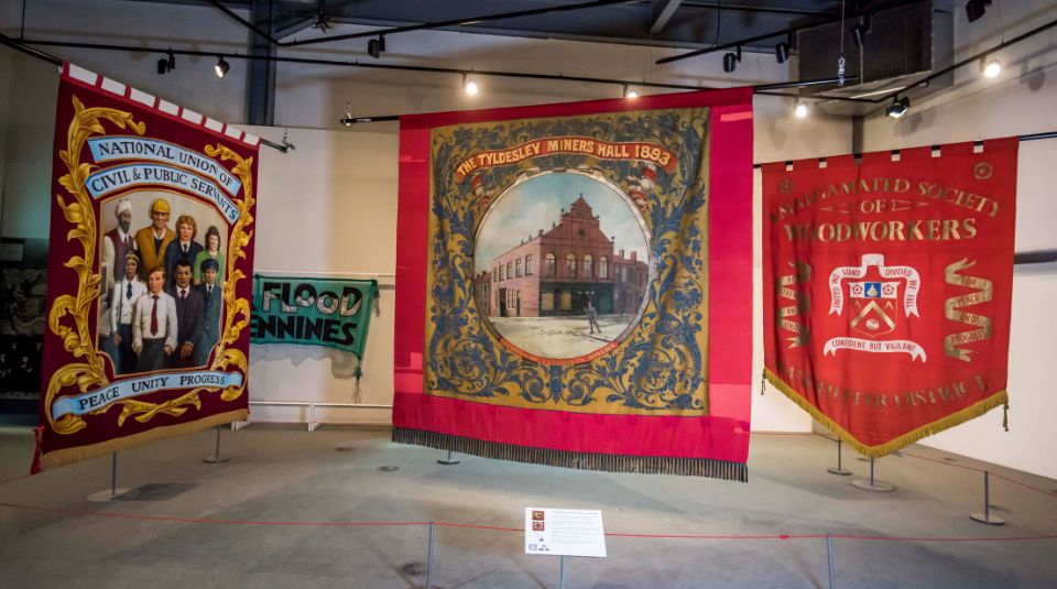 Image of Three big colourful textile banners hanging in a large gallery space.