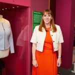 Anglea Rayner MP next to a pale blue round neck zip up jacket with two front pockets on a mannequin in a case at People's History Museum