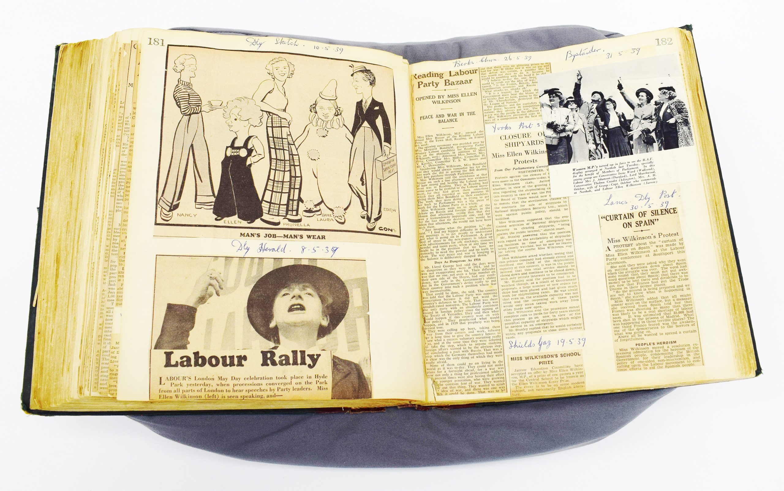 An open scrapbook including black and white newspaper cuttings, illustrations, and photographs.