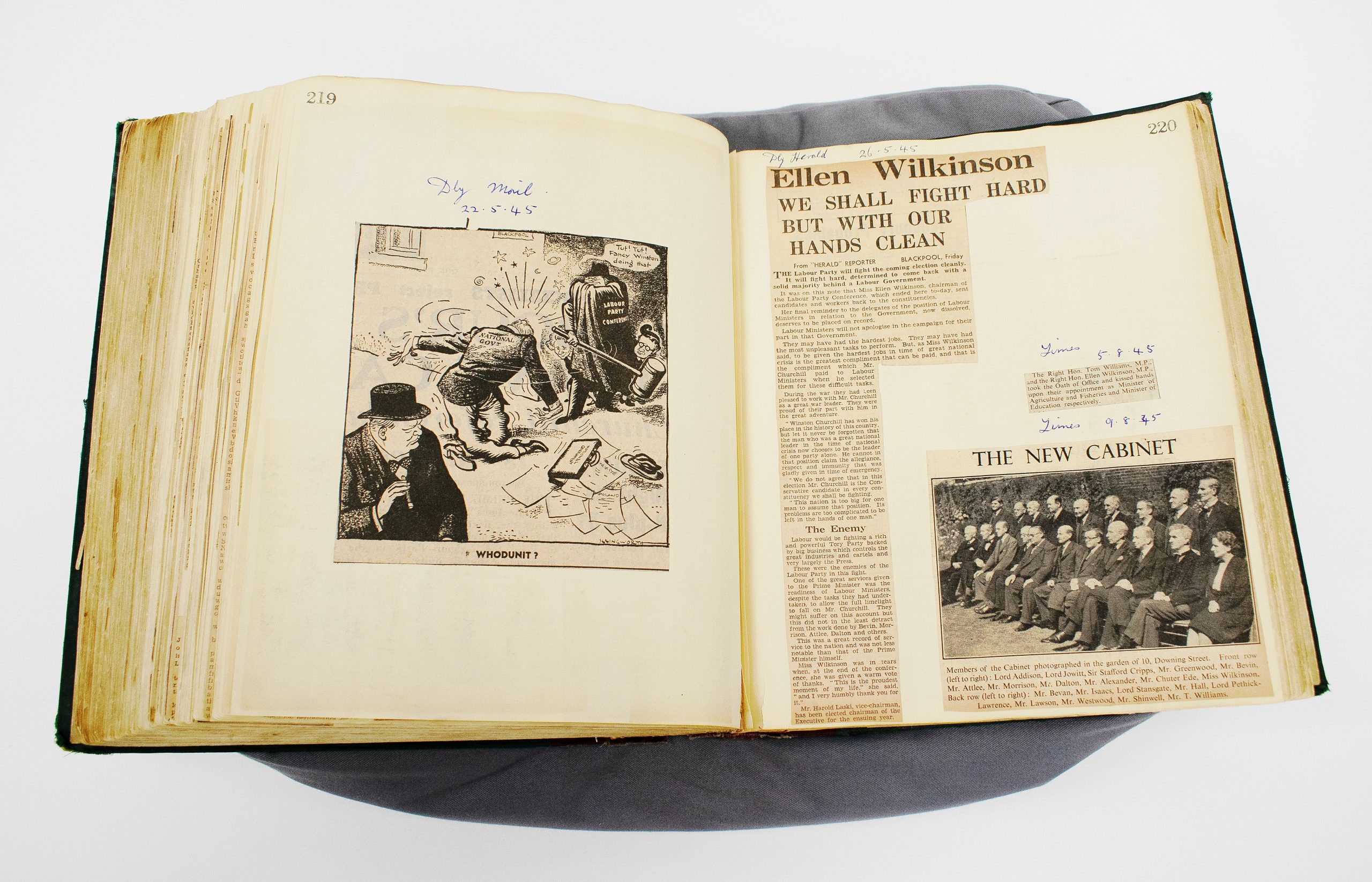 An open scrapbook including black and white newspaper cuttings, a photograph, and an illustration