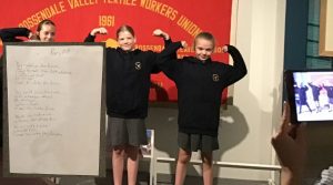 Left to right a written piece of text about years ahead in the future and Students standing in front of a banner, holding their arms up to show strength