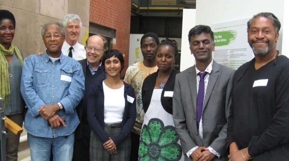 Image of Nine people pose in front of an exhibition which is displayed on white boards in the background.