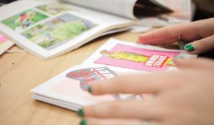 Image of A photograph showing a close up of someone's hands holding open a small zine.