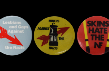 Image of A trio of badges. Left to right the text reads: 'Lesbian and Gays Against the Nazis', 'Miners Against The Nazis', and 'Skins Hate the NF'.