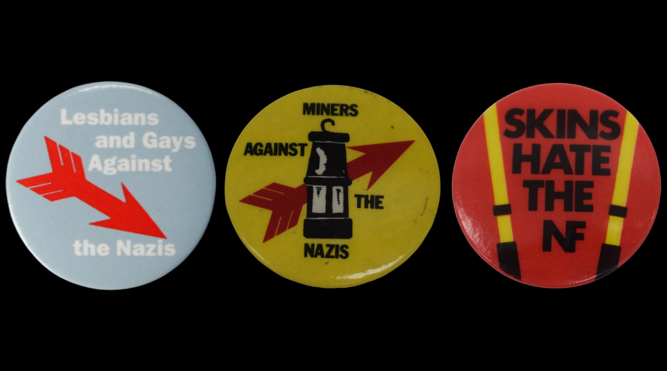 Image of A trio of badges. Left to right the text reads: 'Lesbian and Gays Against the Nazis', 'Miners Against The Nazis', and 'Skins Hate the NF'.