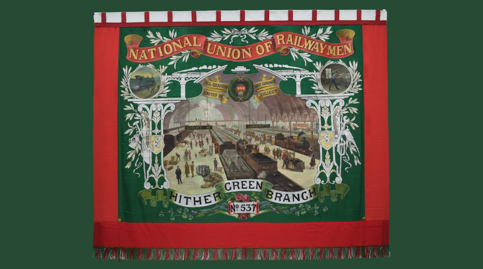 Image of Historic red and green banner including text: 'National Union Of Railwaymen, Hither Green Branch, No 537' and an illustration of a busy train station.