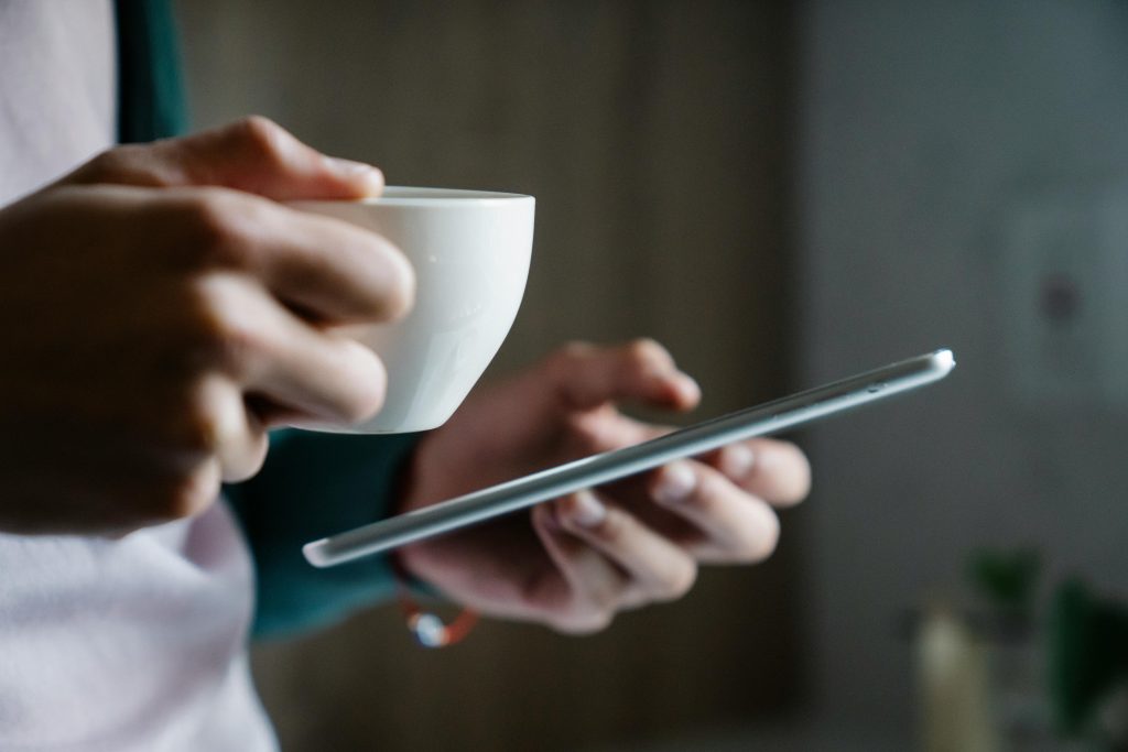 Image of Hands holding a small cup and a mobile phone reading favourite blogs