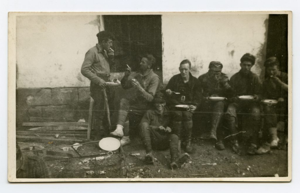 A photo of six men chatting and eating