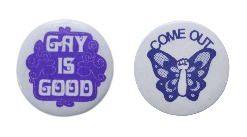 Small white badge with a cloud-like design in purple. ’GAY IS GOOD’ in white in the centre and Round white badge, ‘COME OUT’ in blue curving around the top edge. In the centre is an illustration of a butterfly, all in blue. The middle 'body' of the butterfly is a raised fist.