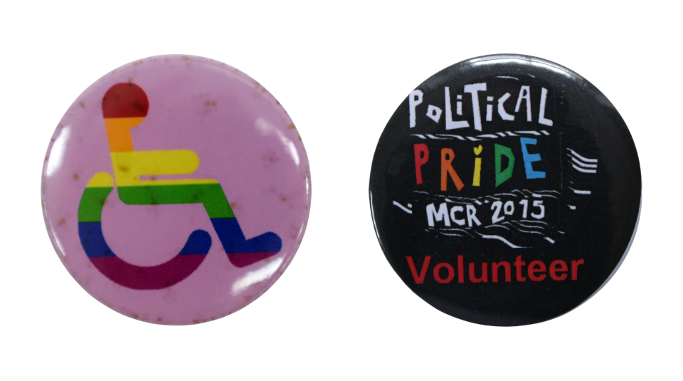 Round pink badge with an illustration of a rainbow striped wheelchair user and a round black badge, with ‘Political Pride MCR 2015 Volunteer’ in white and red. The word 'Pride' is written in the rainbow colours of the Pride flag