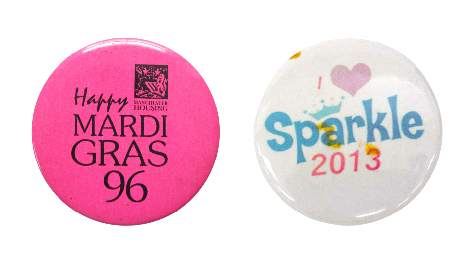 Circular bright pink badge with text reading ’Happy MARDI GRAS 96’ under a logo for Manchester Housing in the top right and a white badge with pink and blue text: 'I heart Sparkle 2013' and a pink heart.