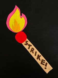 A lit match made from felt pieces on a black background