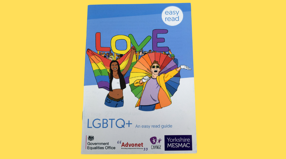 Image of A blue and white booklet titled ‘LGBTQ+ An easy read guide’ with illustrations of two smiling people beneath the word ‘LOVE’ in rainbow colours. One figure is a Black person with long hair holding a rainbow flag behind their back like a cape, the other is a light skinned person in a yellow jacket holding a rainbow umbrella.