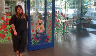 Image of A person stood next to a decorated display case containing a guitar