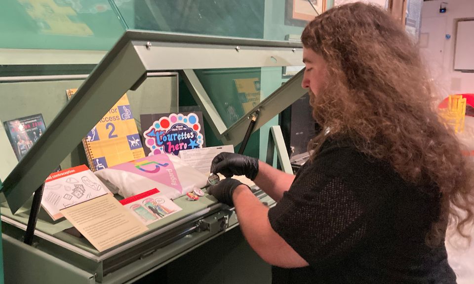 Person with gloved hands adding objects to a display case