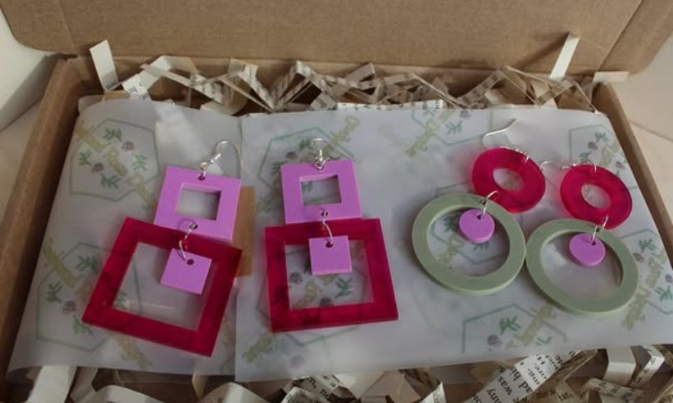 2 pairs of colouful earings laid in a cardboard box