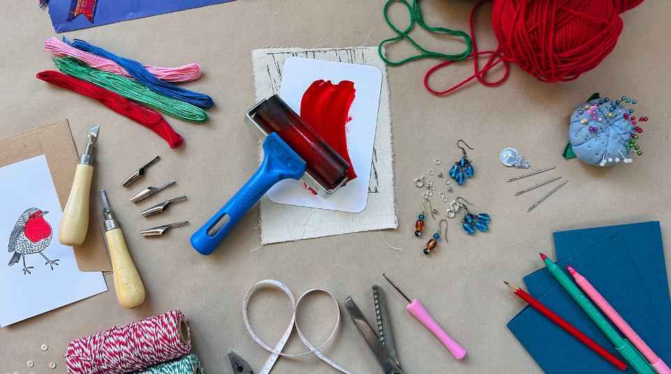 Image of Colourful materials laid out including ribbons, thread, wool, ink roller and string