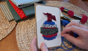 Image of Hands sewing a bauble design onto a Christmas card
