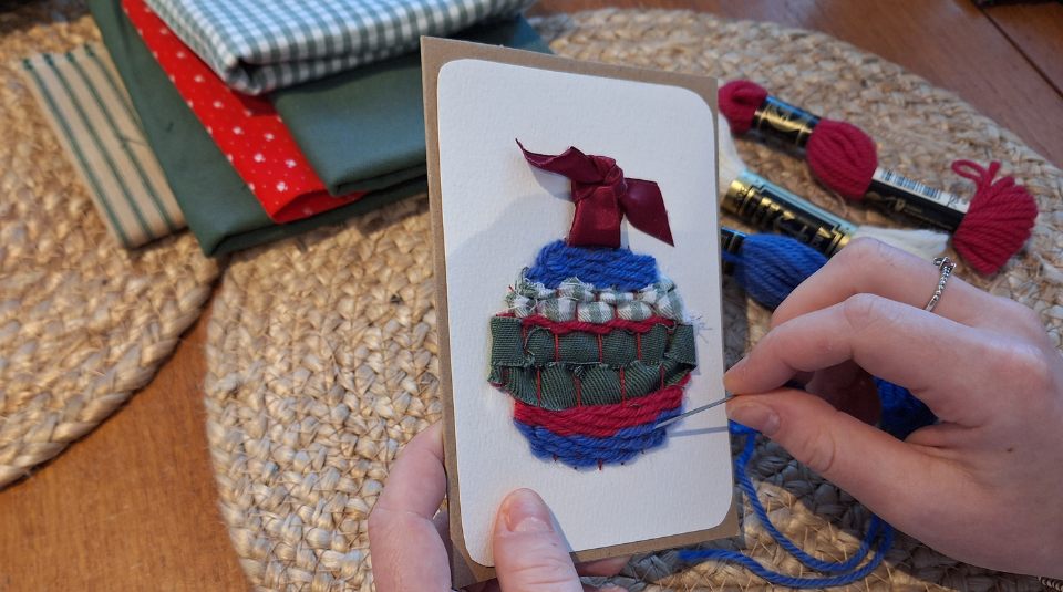 Image of Hands sewing a bauble design onto a Christmas card