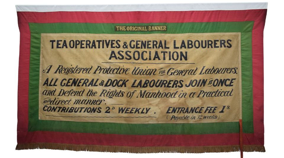 Image of A cream banner with a red and green border. The black text includes Tea Operatives & General Labourers Association