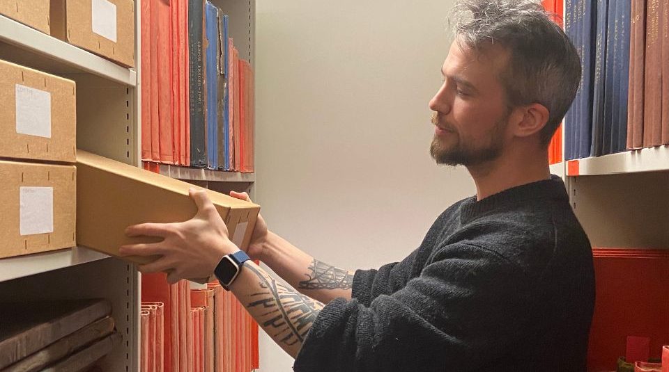 Image of A person holding a box in an archive store