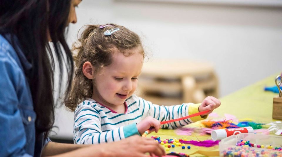 Image of Child enjoying craft activity at People's History Museum Image of A child sat with an adult at a craft table