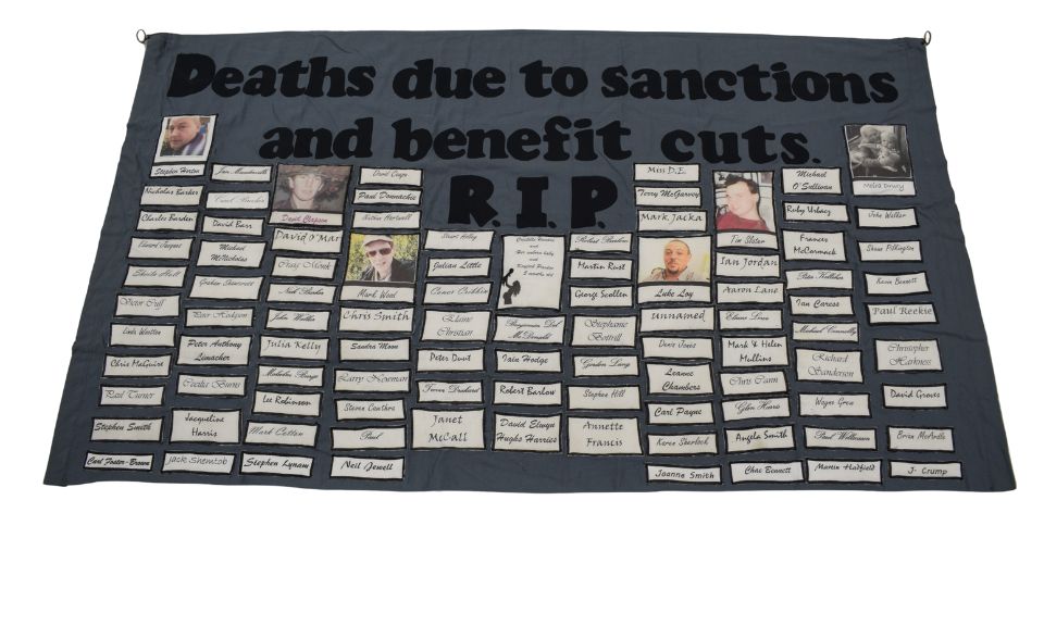 Benefit Cuts Deaths banner, 2015-20 [NMLH.2025.14. Image courtesy of People's History Museum A dark grey banner stitched with names. The text includes Death due to sanctions and benefit cuts RIP