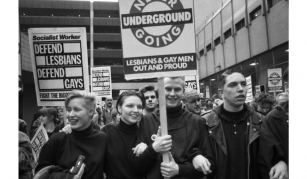 Image of A black and white photograph of people marching holding placards. One reads 'Never Going Underground - Lesbians & Gay Men Out and Proud'