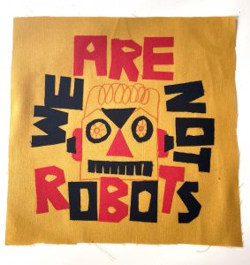 A fabric sample. The red and black test reads WE ARE NOT ROBOTS